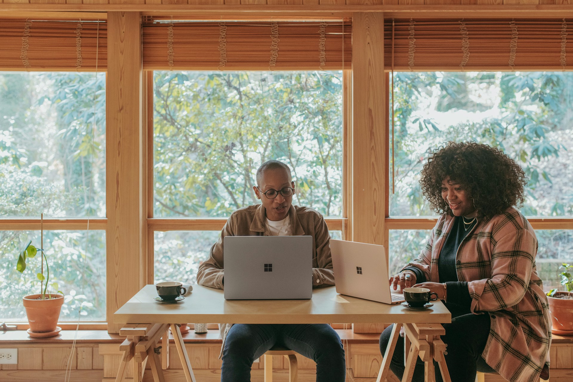 two people in a workspace working on their laptops 